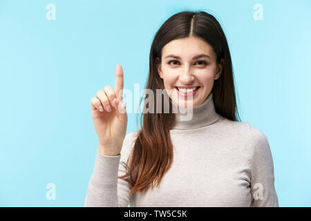 beautiful young caucasian woman pressing a virtual button, looking at camera smiling, isolated on blue background Stock Photo