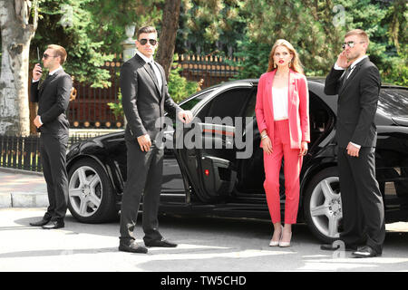 Famous celebrity with bodyguards near car outdoors Stock Photo - Alamy