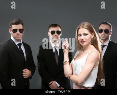 Famous celebrity with bodyguards on grey background Stock Photo