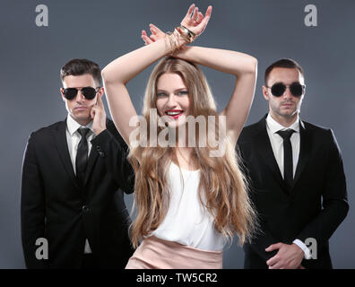 Famous celebrity with bodyguards on grey background Stock Photo