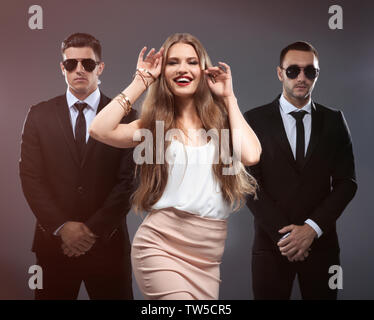 Famous celebrity with bodyguards on grey background Stock Photo