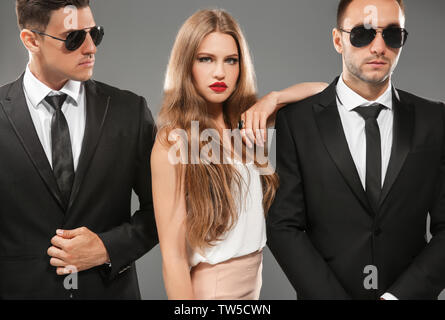 Famous celebrity with bodyguards on grey background Stock Photo