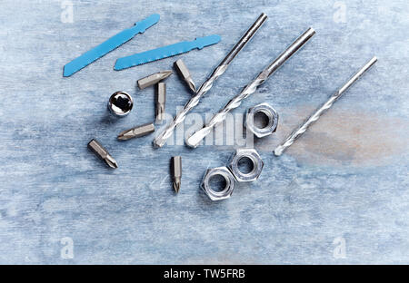 Bits for a screwdriver and hex nuts on wooden background. Top view. Copy space. Stock Photo