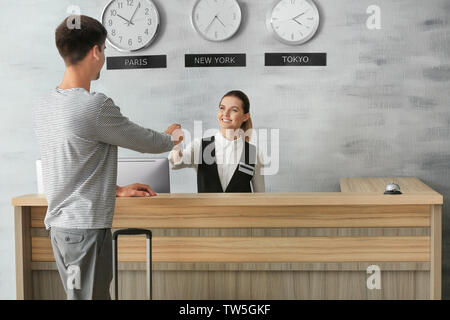 Young man at reception desk in hotel Stock Photo