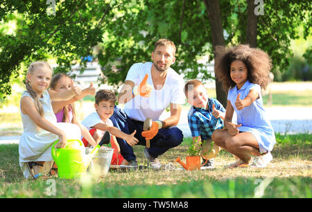 Group of children with teacher planting sapling in park Stock Photo