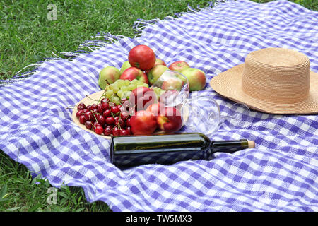 Composition with fruits and wine on blanket in park Stock Photo