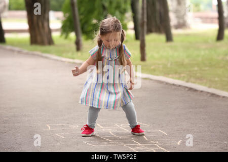 Cute little girl playing hopscotch, outdoors Stock Photo