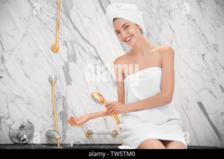 Beautiful young woman going to take shower in bathroom Stock Photo