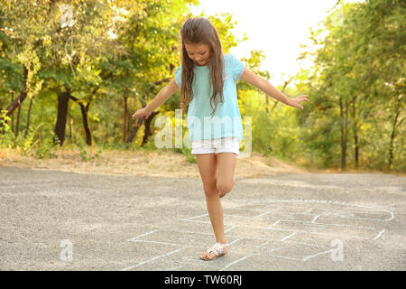 Cute little girl playing hopscotch, outdoors Stock Photo