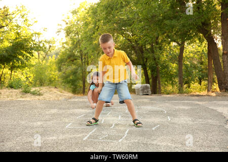 Cute little children playing hopscotch, outdoors Stock Photo