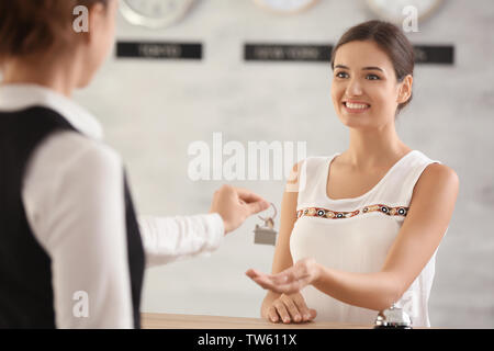 Female receptionist handing room key to woman in hotel Stock Photo