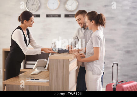 Young couple paying for hotel room at reception Stock Photo