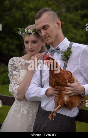 Wedding couple embrace across farm fence with chicken