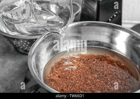 Pouring water into bowl with boiling rice Stock Photo