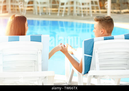 Happy young couple resting near swimming pool at resort Stock Photo