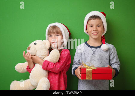 Cute little children with Christmas presents on color background Stock Photo
