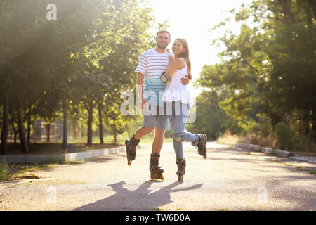 Young couple rollerskating in park Stock Photo