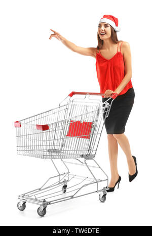 Beautiful young woman in Santa Claus hat and with empty cart on white background. Christmas shopping concept Stock Photo