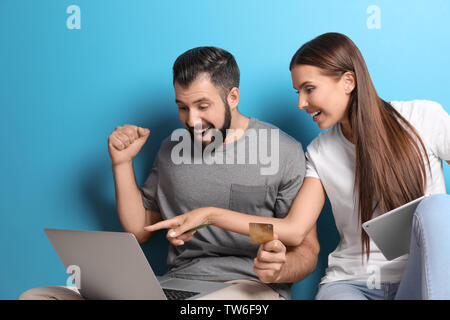 Young couple with laptop and tablet computer on color background. Internet shopping concept Stock Photo