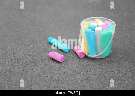 Multicolored chalk in bucket on asphalt Stock Photo