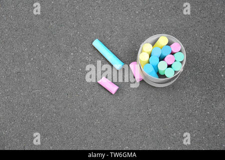 Multicolored chalk in bucket on asphalt Stock Photo