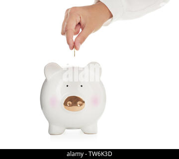 Woman putting coin into cute piggy bank against white background Stock ...