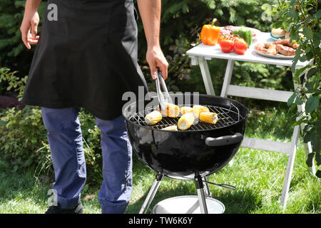 Man preparing delicious corn on barbecue grill outdoors Stock Photo