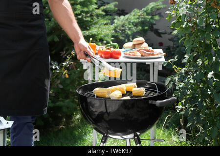Man preparing delicious corn on barbecue grill outdoors Stock Photo