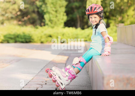 Little girl on roller skates in summer park Stock Photo