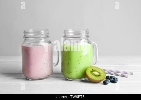 Mason jars with fresh protein shakes on table against white background Stock Photo