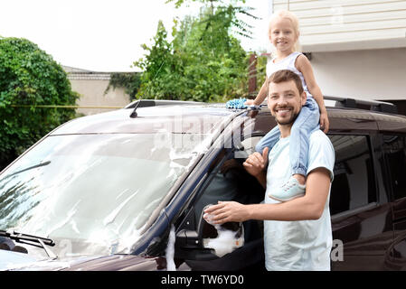 Man with little daughter washing car outdoors Stock Photo