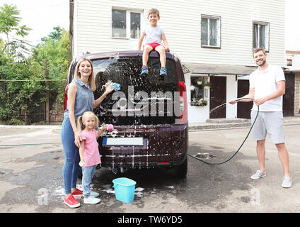 Happy family washing car outdoors Stock Photo