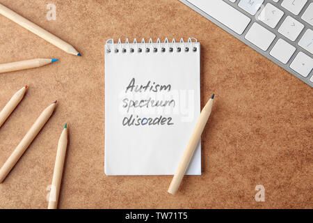 Words "Autism spectrum disorder" written in notebook on table Stock Photo