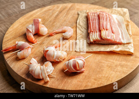 Wooden board with bacon-wrapped shrimps on table Stock Photo