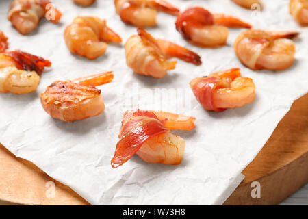 Shrimps wrapped in bacon on wooden board, closeup Stock Photo