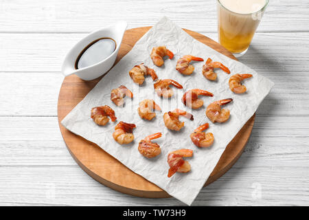 Board with shrimps wrapped in bacon on table Stock Photo