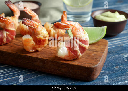 Board with shrimps wrapped in bacon on table Stock Photo