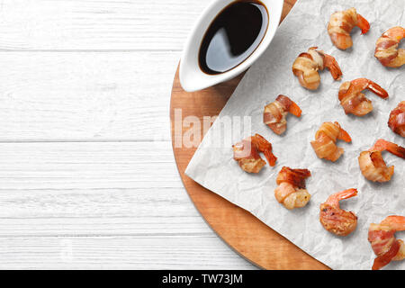 Board with shrimps wrapped in bacon on table Stock Photo