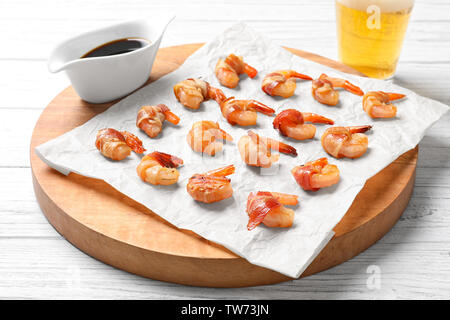 Board with shrimps wrapped in bacon on table Stock Photo