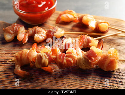 Skewered shrimps wrapped in bacon on board, closeup Stock Photo