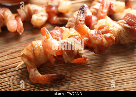 Skewered shrimps wrapped in bacon on board, closeup Stock Photo