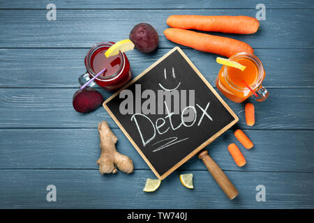 Small chalkboard with word DETOX, fresh juices in mason jars and ingredients on table Stock Photo