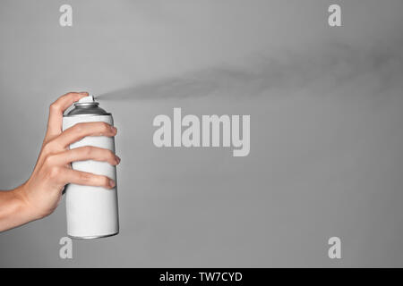 Woman spraying paint from can on grey background Stock Photo