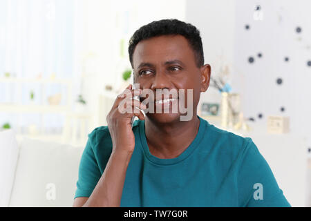 Mature African-American man talking on mobile phone at home Stock Photo