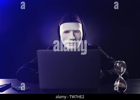 Masked man hacking server in darkness Stock Photo