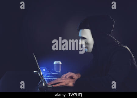 Masked man hacking server in darkness Stock Photo