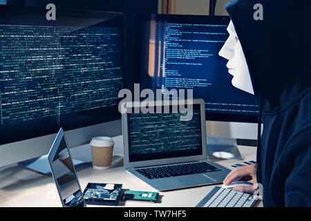 Masked man hacking server in dark room Stock Photo
