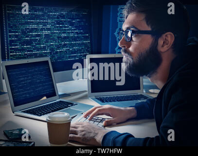 Young man hacking server in dark room Stock Photo