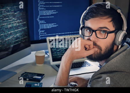 Man with headphones hacking server in dark room Stock Photo