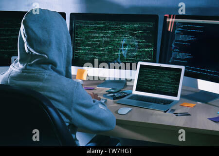 Man wearing hoodie hacking server in dark room Stock Photo